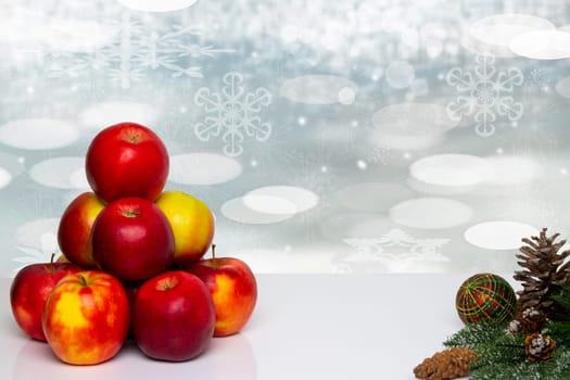 Christmas background. Table top christmas winter decoration background with an apple pyramid and xmas tree fir branches over beautiful abstract white snow landscape. Space for design. Card concept.