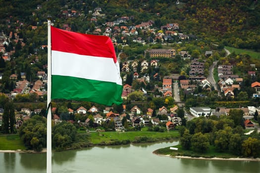 The Hungarian flag is outdoors in Visegrad town in Hungary on village background.