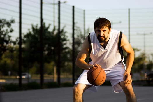 The bearded basketball player is playing outdoors.