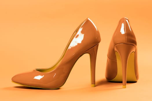 Sexy beige high heels shoes are on beige background.