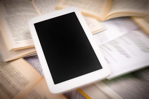 The white digital tablet with black display is on books. Digitalisation concept.