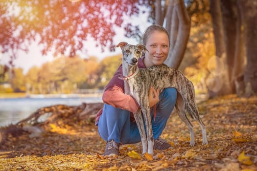 a young girl cuddles with her whippet dog