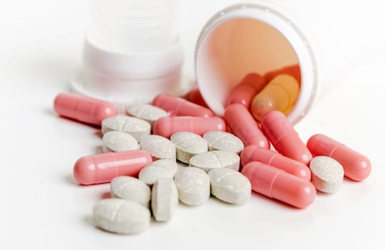 Pills and capsules in a jar on a white background