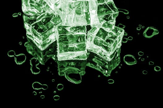 Hill of green ice cubes on a black glass with water drops.