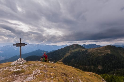 Male hiker with backpack relaxing on top of a mountain - scenery from vacation - photo with space for your montage.