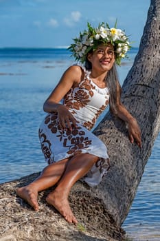 Young woman with flower wreath from Frangipani leans against palm trunk,Raiatea,French Polynesia