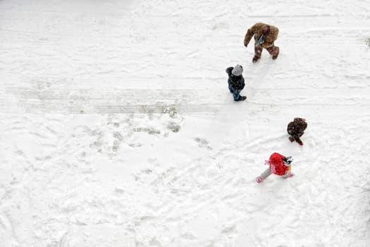Elevated view of family play in snow covered parking lot
