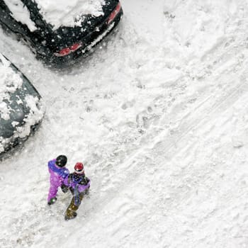Elevated view of children play in snow covered parking lot