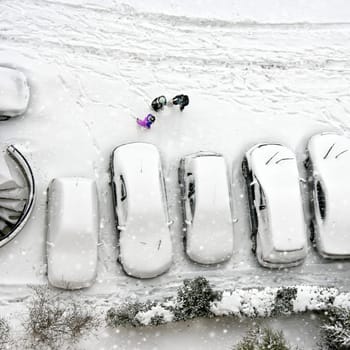 Elevated view of children play in snow covered parking lot