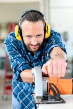 young worker with hand saw in a carpenter's workshop