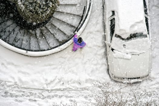 Elevated view of child play in snow covered parking lot