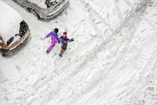 Elevated view of children play in snow covered parking lot