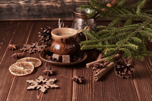 Cup of coffee, fir tree branches with decorations on a wooden brown background. Christmas and New Year treat.