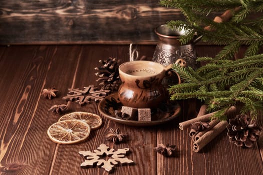Cup of coffee, fir tree branches with decorations on a wooden brown background. Christmas and New Year treat.
