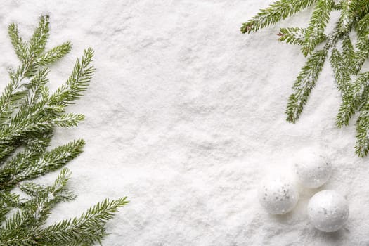 Fir tree branches with decorations and gift box on a snow background with copy space. Top view. Christmas and New Year. Winter holiday. Greeting card