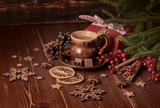 Cup of coffee, gift box, fir tree branches with decorations on a wooden brown background. Christmas and New Year.