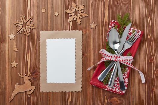 Spoon, knife and fork on red napkin with fir tree branch on a wooden background. Top view with copy space for adding your content. Menu. Advertising