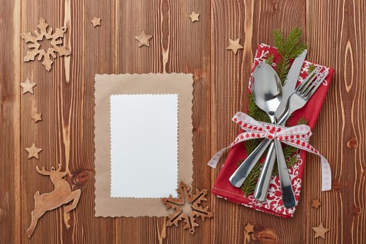 Spoon, knife and fork on red napkin with fir tree branch on a wooden background. Top view with copy space for adding your content. Menu. Advertising