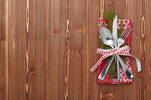 Spoon, knife and fork on red napkin with fir tree branch on a wooden background. Top view with copy space for adding your content. Menu. Advertising