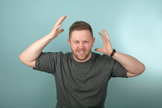 Frustrated angry man snarling and gesturing with his hands either side of his head over a grey background