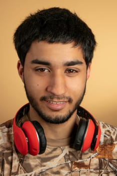 Young Man with Headphones listen to Music on beige Background