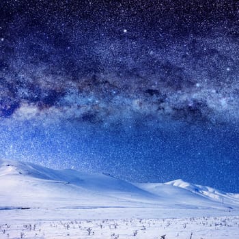 Snow covered empty frozen landscape of mountainside over night sky with stars of galaxy. NASA galaxy images manipulated and used https://nasasearch.nasa.gov/search/images?utf8=%E2%9C%93&affiliate=nasa&query=galaxy+images