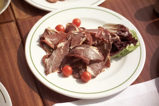 close up plate of sliced pastrami arrangement on breakfast table