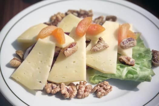 close up plate of cheese and dried fruits with walnut on breakfast table