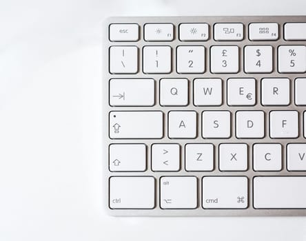 Detail of a modern aluminum computer keyboard with white keys view from above