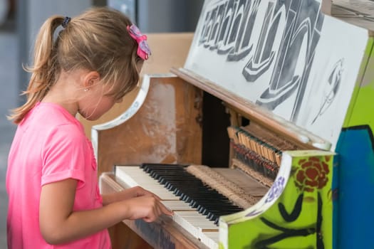 Little young caucasian girl playing on the piano outside train station