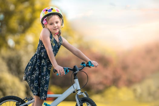 Portrait of an adorable young Caucasian girl with her bicycle in a public park