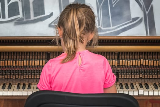 Little young caucasian girl playing on the piano outside train station