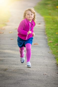 Little Caucasian girl running fast in the park in spring