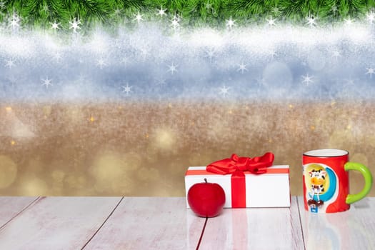 Christmas or winter decoration background. Christmas white gift box with an apple and a funny cup on a rustic wooden table. Closeup.