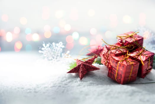 Red star and gift boxes on snow with blurred lights background. Christmas decoration
