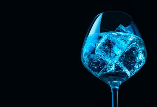 Glass of wine with ice cubes over black background