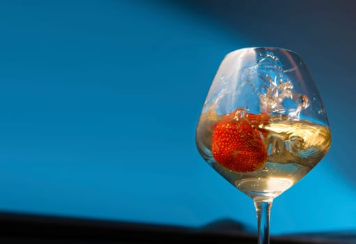 Wine glass with strawberries inside it over colored background