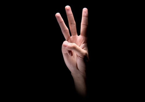 Male hands with three finger sign over dark background