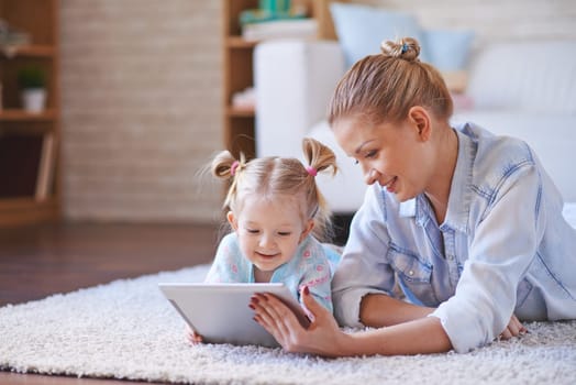 Cute child and her mother with digital tablet relaxing at home