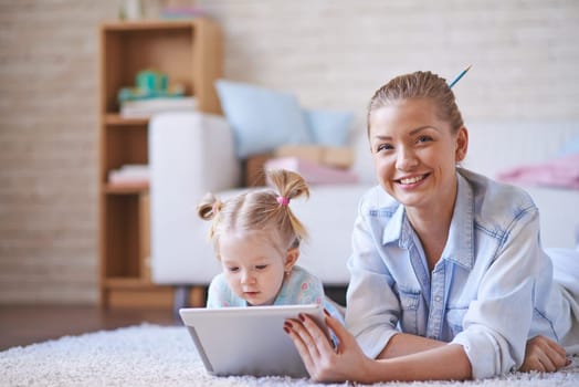 Cute little girl and her mother spending weekend with digital tablet at home