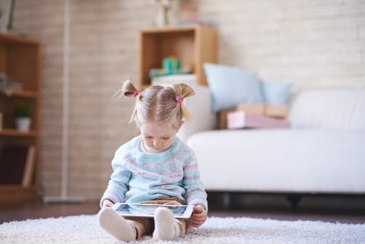 Adorable child with touchpad sitting on the floor at home