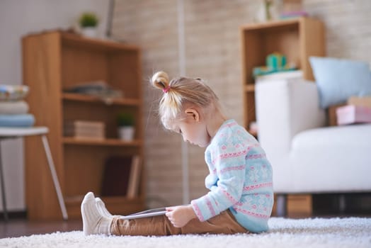 Little girl with digital tablet sitting on the floor