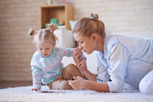 Cute little girl and young woman using digital tablet while spending time at home