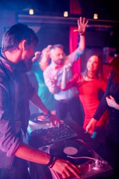 Male deejay adjusting sound with group of dancing friends near by
