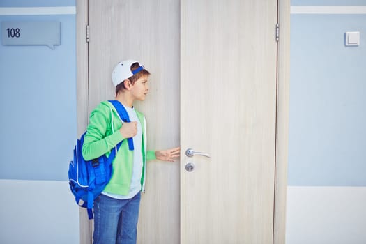 Pre-teen schoolboy opening classroom door and looking inside