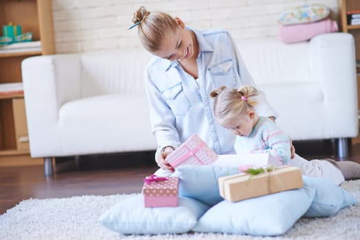 Happy woman showing her little daughter giftboxes with presents