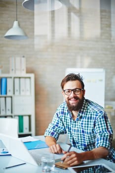 Bearded businessman in casualwear sitting at workplace