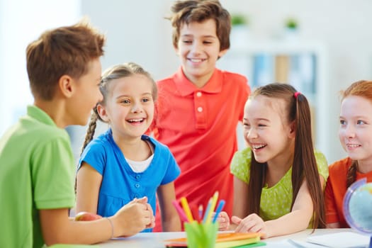 Friendly boys and girls talking and laughing at break in school