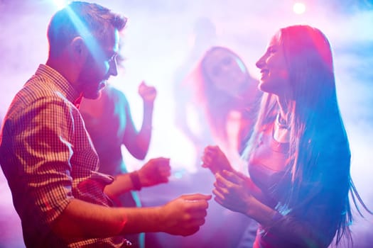 Happy young couple dancing in night club