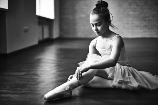 Adorable ballerina tying up her shoes